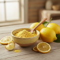 Organic lemon powder in a ceramic bowl with fresh lemons and lemon slices on a wooden surface